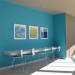 Three paintings on a bright blue wall over a seating area