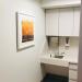 painting of autumn trees with orange and yellow leaves hangs next to a sink in an examination room