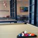 A billiard table with artwork and a meeting space in the background
