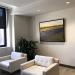 a framed painting hangs above two chairs
