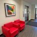 colorful framed artwork hangs above red chairs