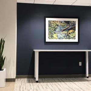 a framed artwork hangs above a table on a black wall