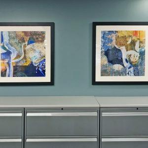 two framed artworks hanging side by side on blue wall